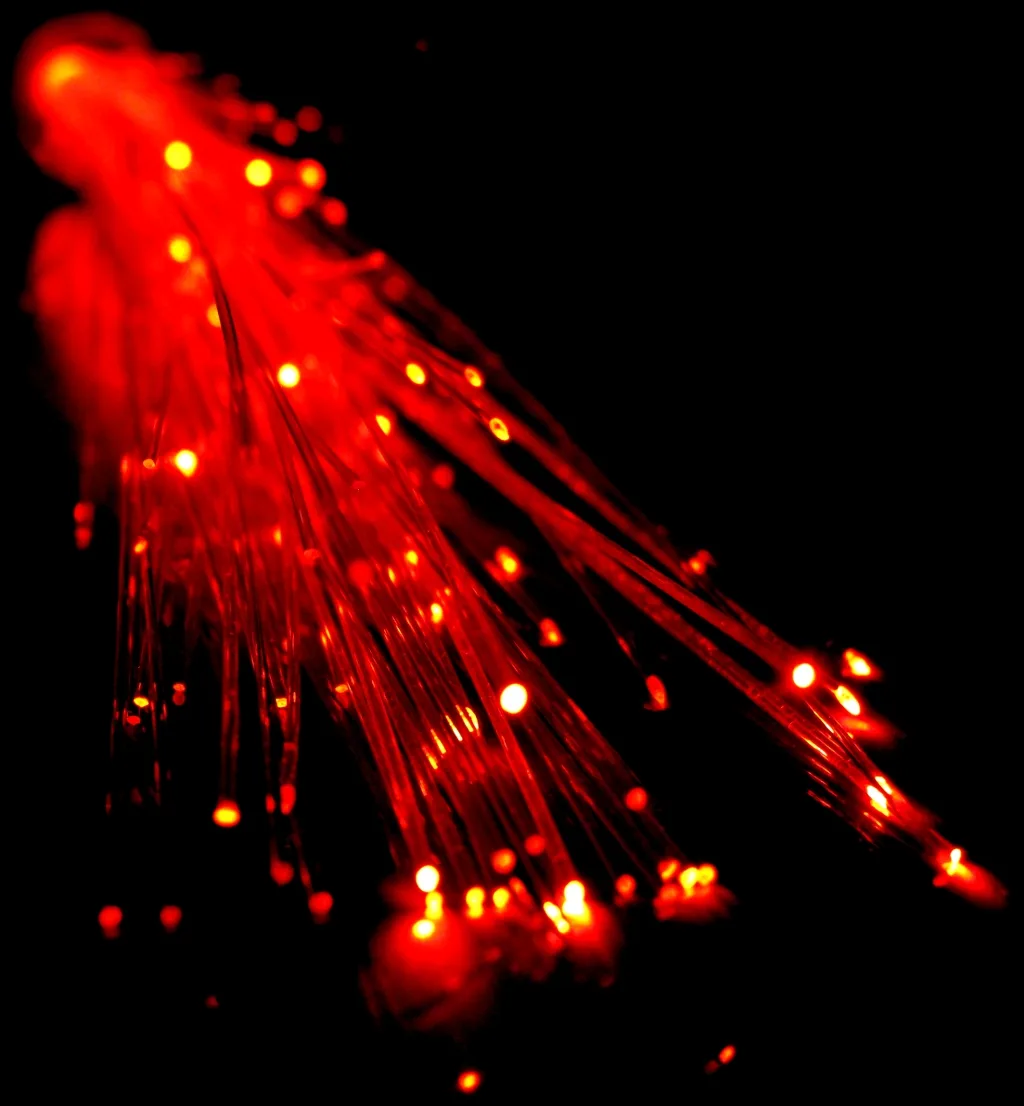 Red-lit optical fibers glowing against black